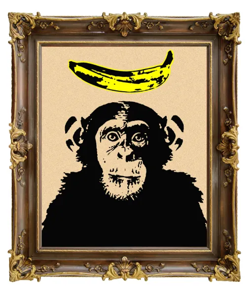 A framed picture features a black-and-white chimp head with a yellow banana sticker on the forehead. The frame is ornate and gold-colored with decorative details.